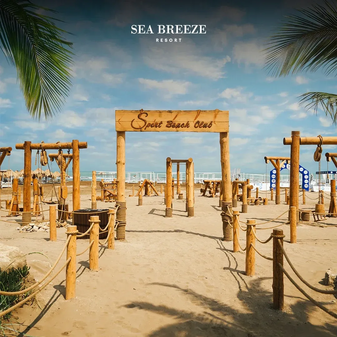 Qumda açıq səma altında zalın taxta trenajorları və Sport Beach Club lövhəsi