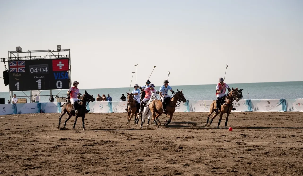 A beach polo match by the sea: riders with mallets and a scoreboard